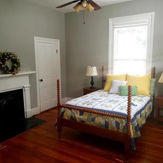A cozy bedroom with a wooden bed, fireplace, and natural lighting.