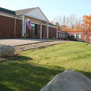 A brick school building with an American flag and a well-maintained lawn on a sunny autumn day.