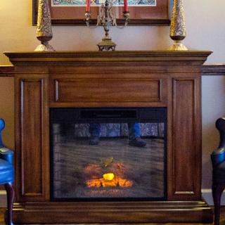 A cozy room with a wooden fireplace and decorative candles on the mantel.