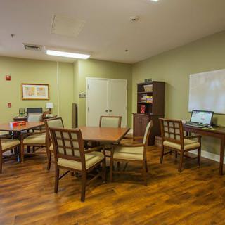 A quiet office space featuring several tables and chairs, a computer, and a bookshelf against green-painted walls.