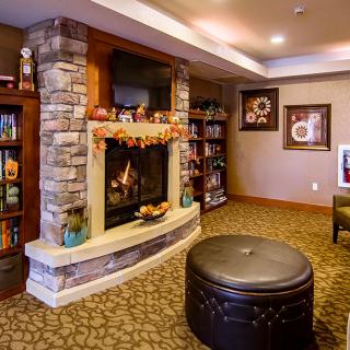 A cozy living room with a stone fireplace, adorned with autumn decorations and surrounded by bookshelves.