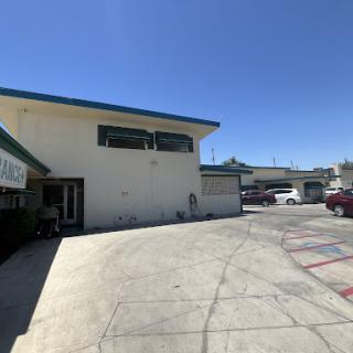 A view of a two-story building with a parking lot under clear blue skies.
