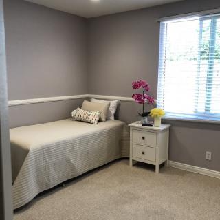 A minimalist bedroom with a single bed, nightstand, and natural light streaming in through the window.