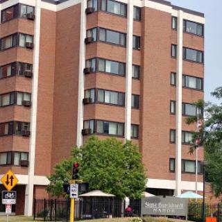 A modern apartment building featuring a brick facade, surrounded by urban landscaping.