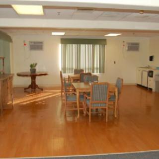 A spacious dining room with wooden floors and a set of tables and chairs.