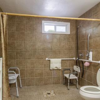 An accessible bathroom equipped with grab bars and a shower chair.
