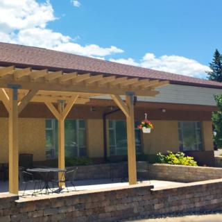A house with a wooden patio structure and outdoor seating on a sunny day.