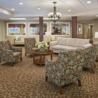 A cozy living room with patterned armchairs, a sofa, and a coffee table set on a carpeted floor.