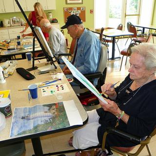 A group of seniors engaged in a painting class, enjoying creative expression together.