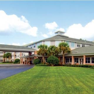A spacious building with a well-maintained lawn and palm trees under a clear sky.