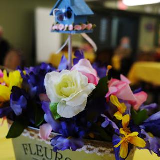 A vibrant floral arrangement featuring a mix of colorful artificial flowers, highlighting a beautiful white rose at the center.
