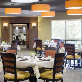 A modern restaurant dining area with set tables and stylish lighting.