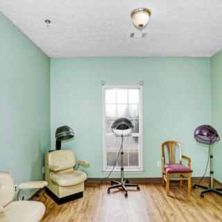 A small hair salon with vintage chairs and hairdryers, featuring mint green walls and a wooden floor.
