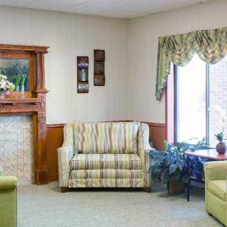 A cozy living room featuring a striped sofa, fireplace, and a large window with elegant drapes.