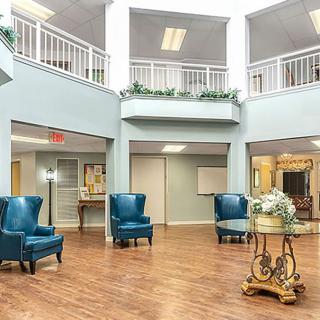 A spacious lobby area with elegant blue chairs and a decorative table on a wooden floor.