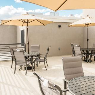 A sunny outdoor patio with tables, chairs, and umbrellas.