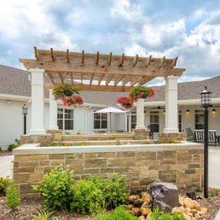 A beautifully designed outdoor space featuring a pergola with hanging flower baskets and elegant landscaping.