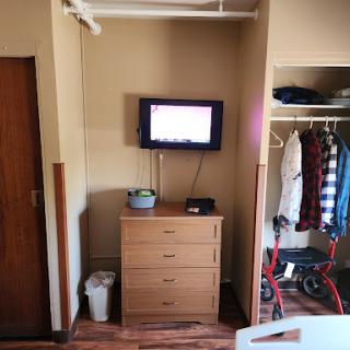 A compact room featuring a dresser, television, and closet.