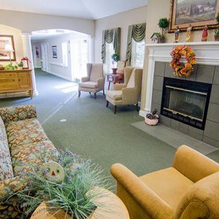 A cozy living room with a fireplace, sofa, and armchairs.