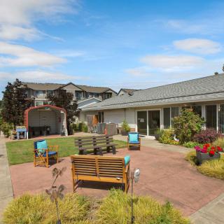 A tranquil outdoor courtyard featuring seating areas and lush landscaping under a clear blue sky.