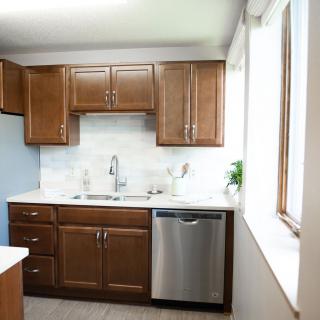 A modern kitchen with wooden cabinets and a stainless steel dishwasher.