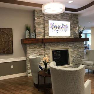 A modern living room with a stone fireplace, elegant armchairs, and warm lighting.
