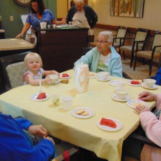 A group of people, including seniors and a child, enjoying a meal together indoors.