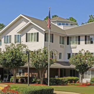 A suburban residential building with well-maintained landscaping and an American flag displayed in front.