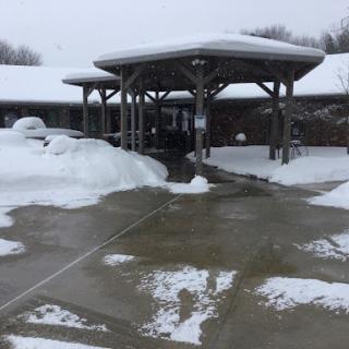 A snowy scene showcasing a building entrance covered in snow with a slushy pathway.