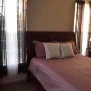 A cozy bedroom with a neatly made bed and light streaming through the curtains.