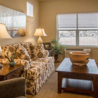A cozy living room with a patterned sofa, wooden coffee table, and warm lighting.
