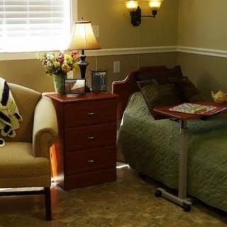 A cozy bedroom with a bed, nightstand, chair, and decorative lamp.