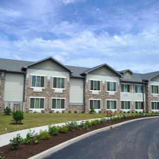 A modern residential building with a landscaped driveway under a blue sky.