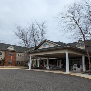 An exterior view of a building entrance with columns and an overcast sky.