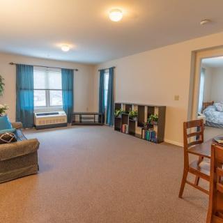 A spacious living room with a sofa, dining area, and large windows adorned with blue curtains.