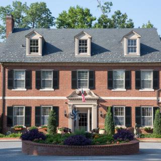 A colonial-style brick house with dormer windows and a well-maintained garden.