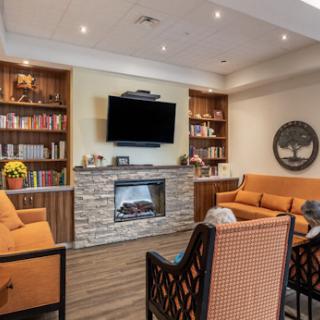 A cozy living room featuring a modern fireplace, built-in bookshelves, and comfortable orange seating.