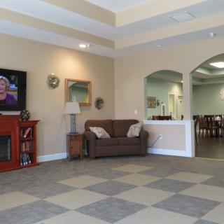 A cozy living room with a sofa, fireplace, and television, featuring artwork and arched doorways.