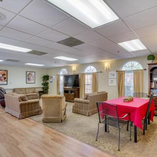 A cozy living room with sofas, a television, and a table covered in a red cloth.