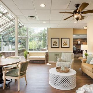A well-lit living room with large windows, featuring comfortable seating and elegant decor.