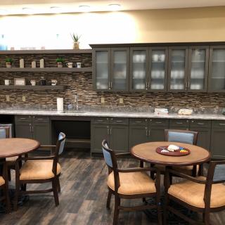 A modern kitchen and dining area with round tables and wooden cabinets.
