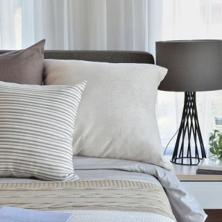 A cozy bedroom setup with soft pillows and a stylish lamp.