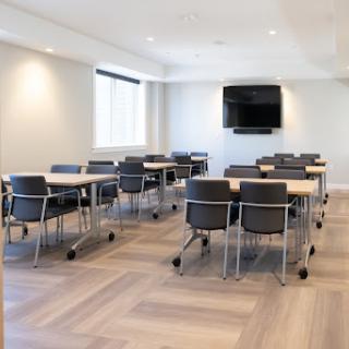 A modern meeting room equipped with tables and chairs, suitable for conferences or workshops.