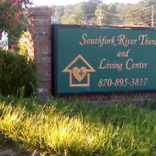 Signage for the Southfork River Therapeutic and Living Center surrounded by greenery.