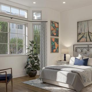 A modern bedroom with natural light, featuring artwork and a potted plant by the window.