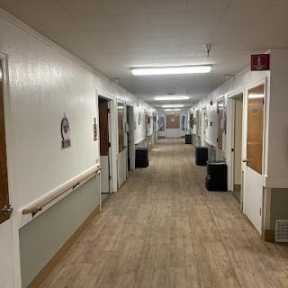 A long, well-lit hallway with multiple doors along the sides.