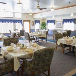 An indoor dining room with tables and chairs, set for a meal.