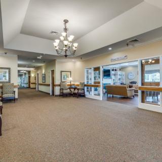 A spacious and well-lit lobby area with a chandelier, carpeted floor, and seating arrangements.