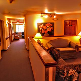 A cozy hallway with warm lighting and a seating area adorned with artwork.