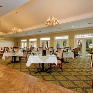 An elegant dining room with neatly arranged tables and chandeliers.